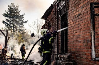 Ukrainian emergency services personnel work to extinguish a fire following a Russian drone attack in Kharkiv region